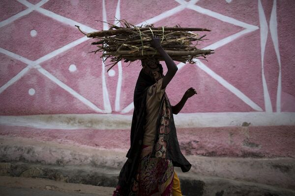 Женщина несет вязанку дров на улице в Харэре