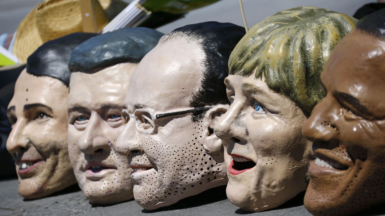 Маски с лицами участников саммита G7 во время акции протеста в Мюнхене