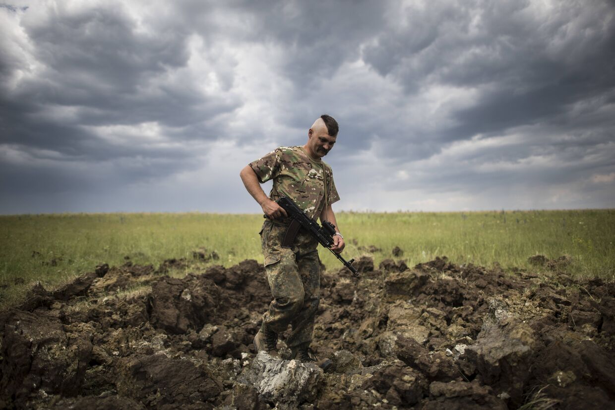 Украинский военный осматривает кратер от ракеты «Град» в деревне Тошковка Луганской области