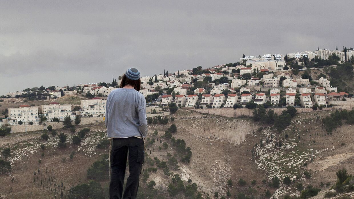 Израильтянин смотрит на город Маале-Адумим на Западном берегу реки Иордан