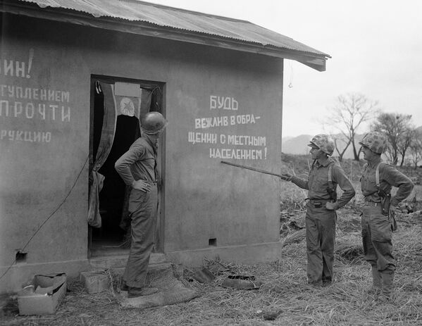 Американские солдаты у корейского домика с надписями на русском на стенах