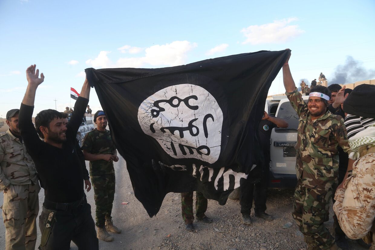 Иракские военные и бойцы шиитских отрядов саммобороны с захваченным флагом Исламского государства