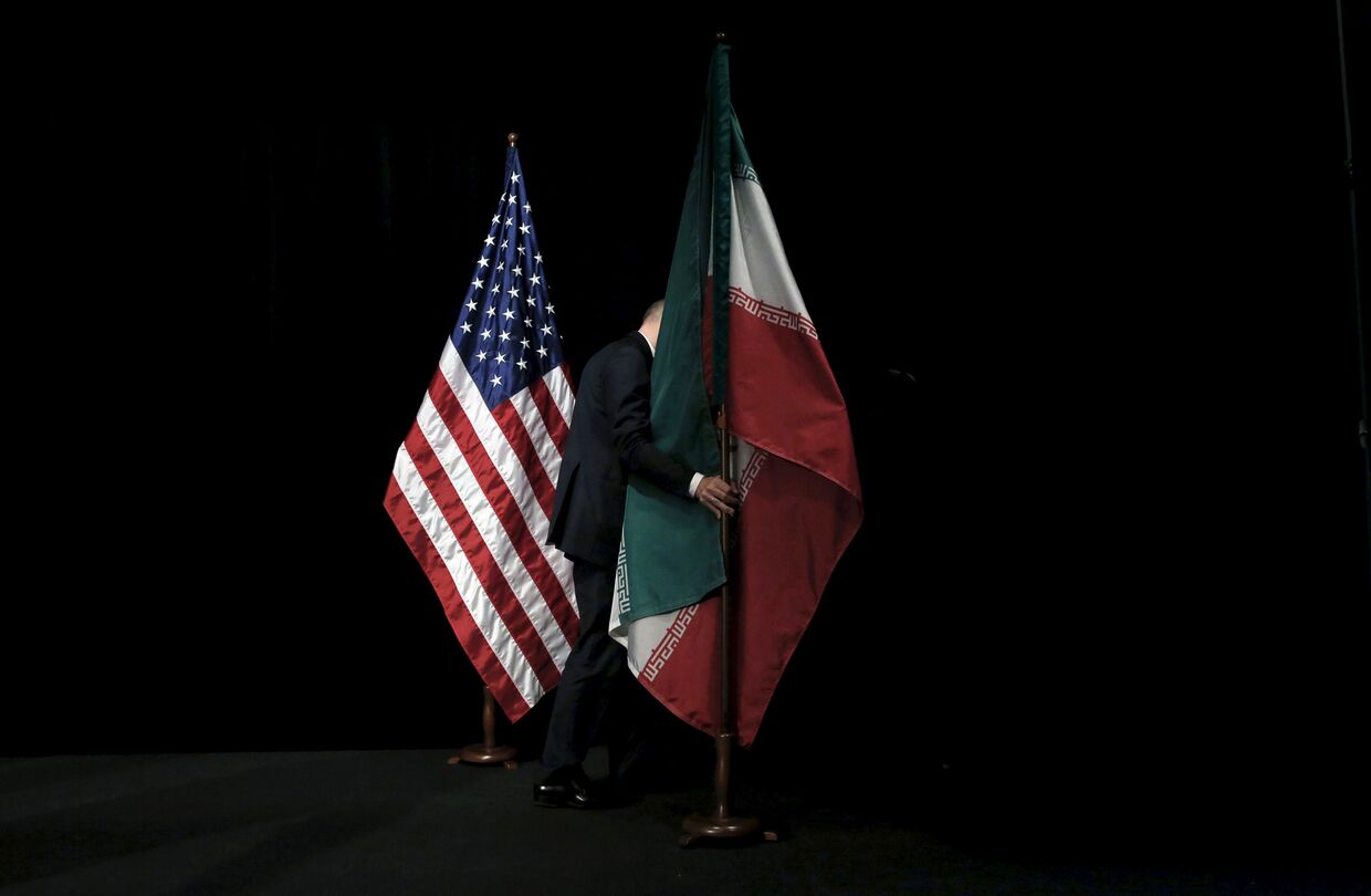 Сотрудник убирает флаги после совместного фотографирования лидеров государств-участников соглашения по иранской ядерной программе