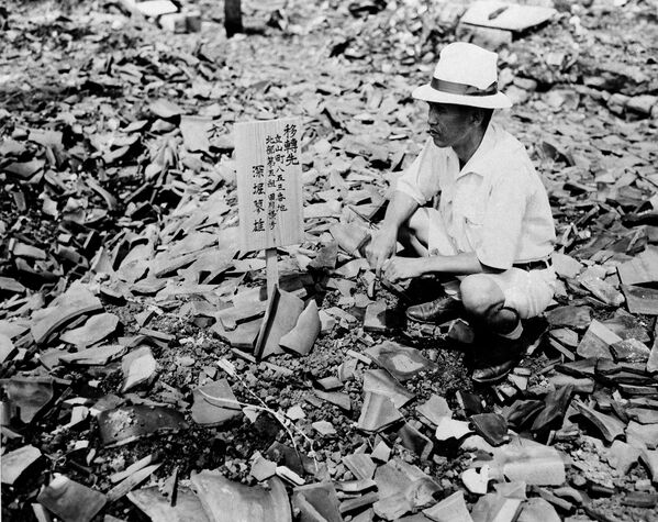 Житель Нагасаки рассматривает знак на месте своего разрушенного дома