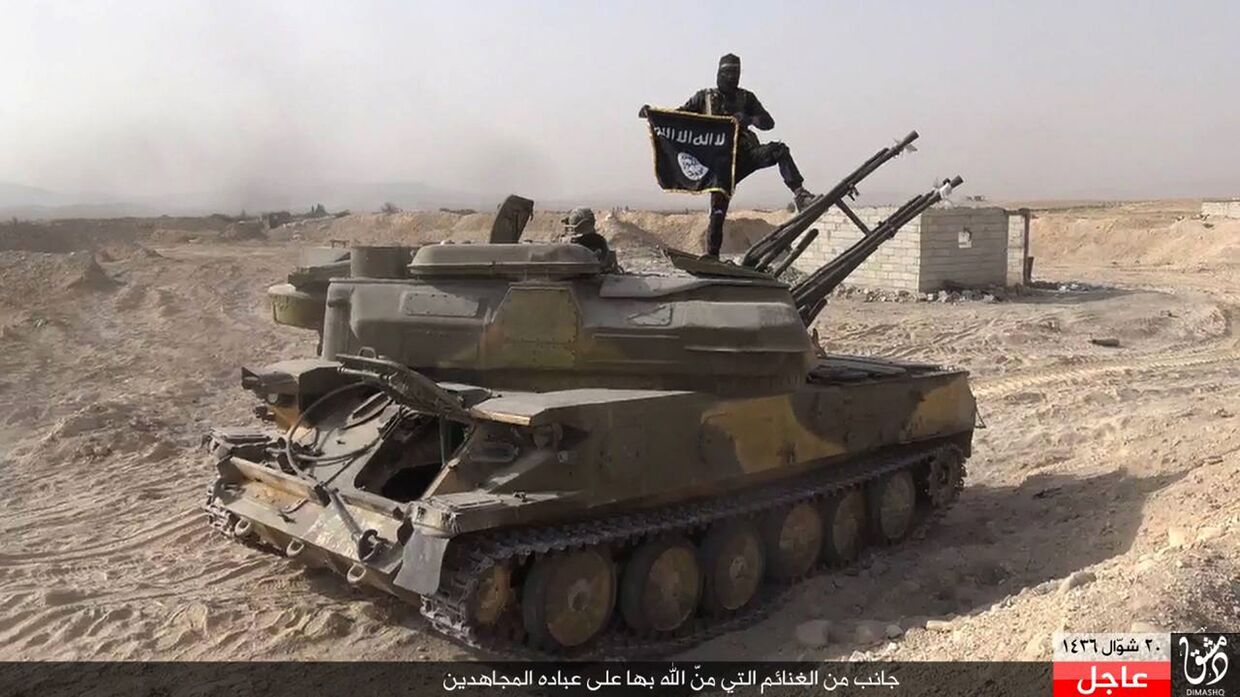 Боец ИГИЛ на танке, захваченном у сирийских военных, в городе Эль-Карьятейн