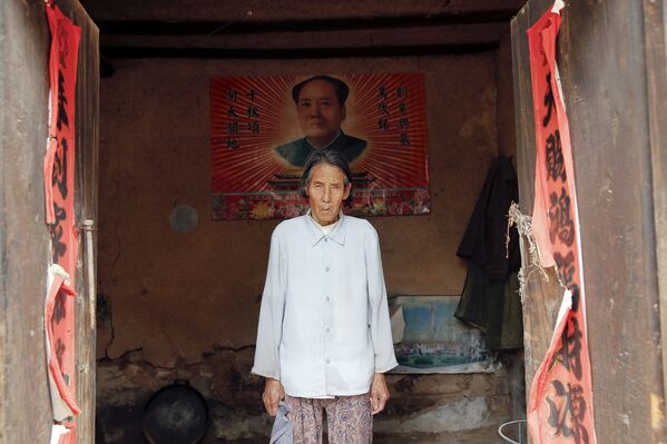 Жэнь Ланэ на фоне портрета Мао Цзэдуна в своем доме в городе Гучэн, провинция Шаньси