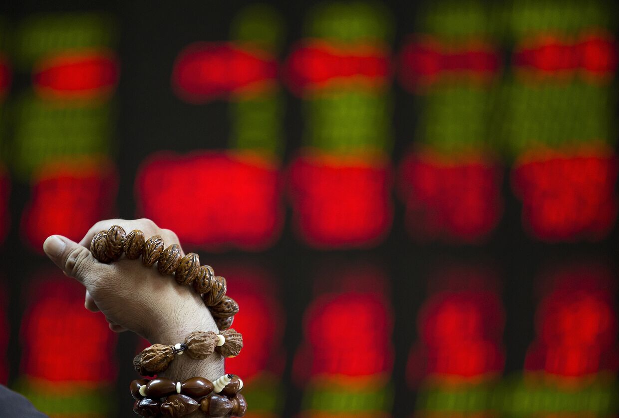 Мужчина перебирает четки на фондовой бирже в Пекине