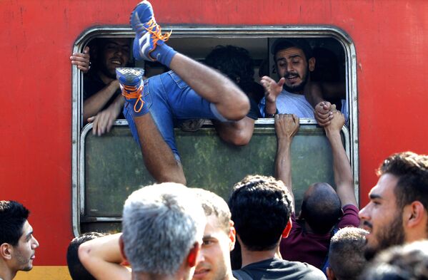 Мигрант влезает в окно поезда, отправляющегося в Сербию со станции в Гевгелии