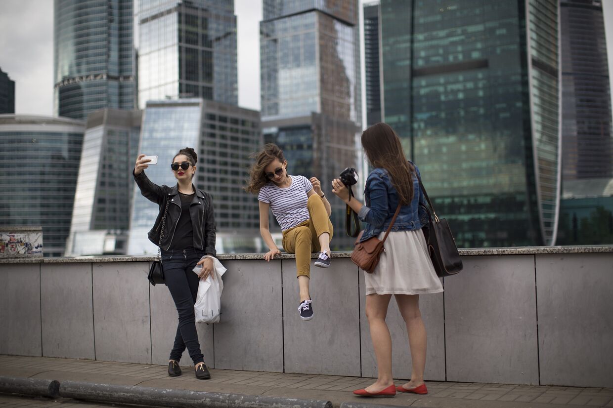 Девушки фотографируются на фоне небоскребов «Москва-Сити»