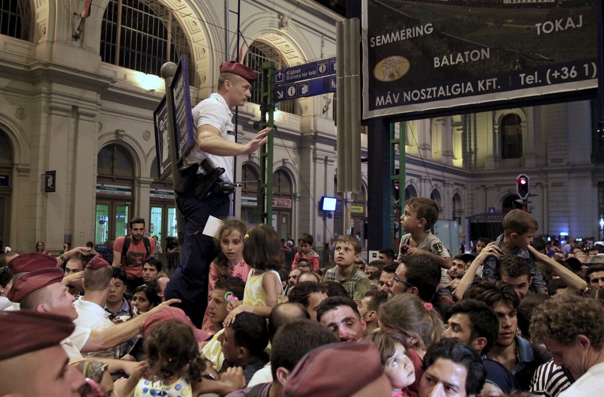 Полицейский пытается контролировать толпу мигрантов на железнодорожном вокзале Будапешта, Венгрия. 31 августа 2015