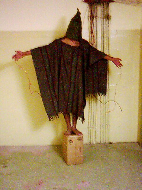 Заключенный тюрьмы Абу-Грейб в Багдаде с мешком на голове и проводами на теле