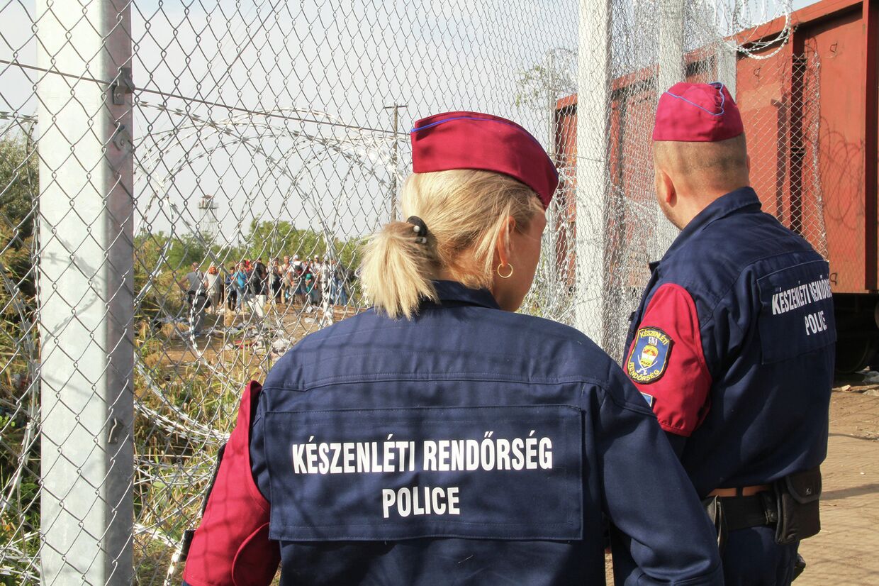 Венгерские полицейские наблюдают за беженцами на сербской стороне