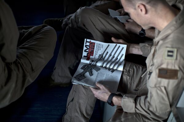 Военный летчик читает журнал об оружии на борту авианосца «Теодор Рузвельт»
