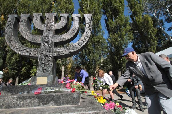 Люди возлагают цветы к памятнику в Национальном историкомемориальном заповеднике Бабий Яр