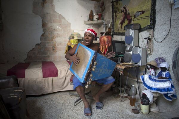 Последователь сантерии Мигель Анхель поет религиозные песни в своем доме в Гаване