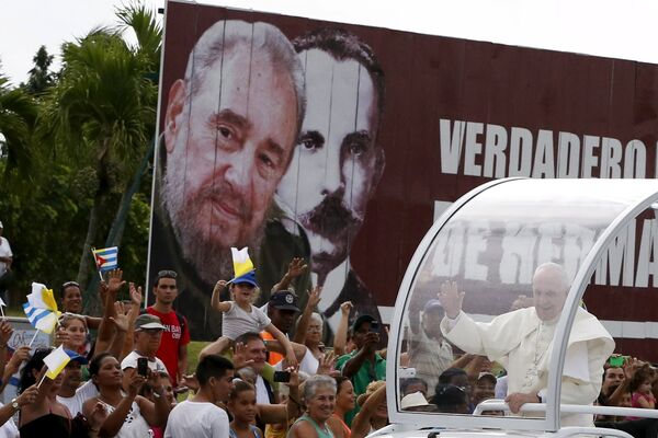 Папамобиль проезжает мимо щита с изображениями Фиделя Кастро и Хосе Марти