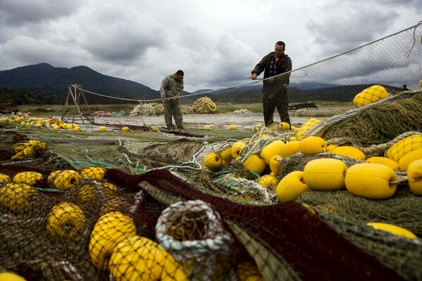 Рыбаки чинят сети на берегу Охотского моря