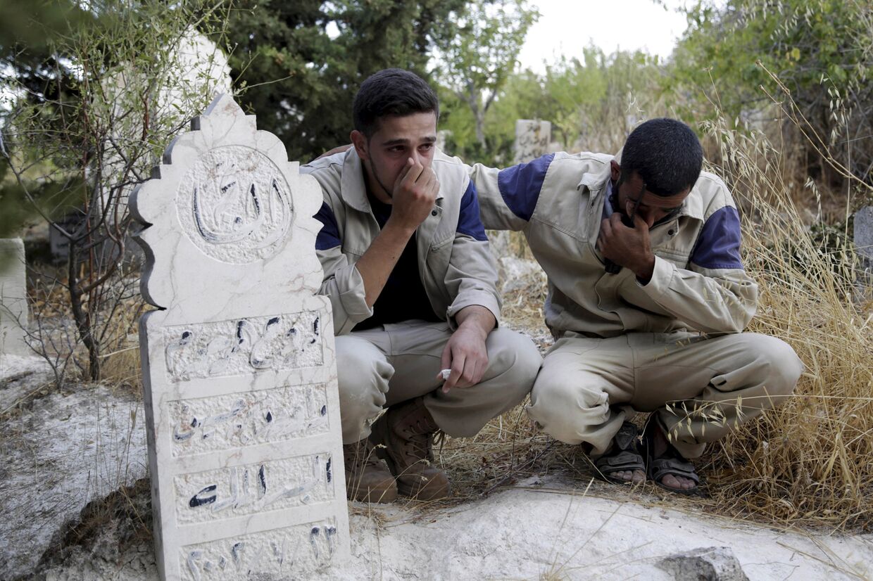Работники группы сирийской гражданской обороны у могилы своего сослуживца, погибшего, по их словам, во время российского авиаудара