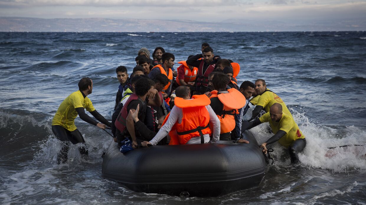 Спасатели помогают беженцам причалить у берега греческого острова Лесбос