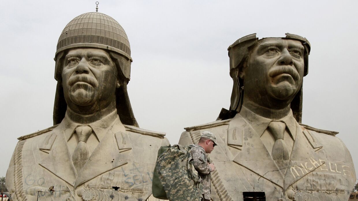Американские солдаты проходят мимо бронзовых бюстов Саддама Хусейна в Зеленой зоне Багдада