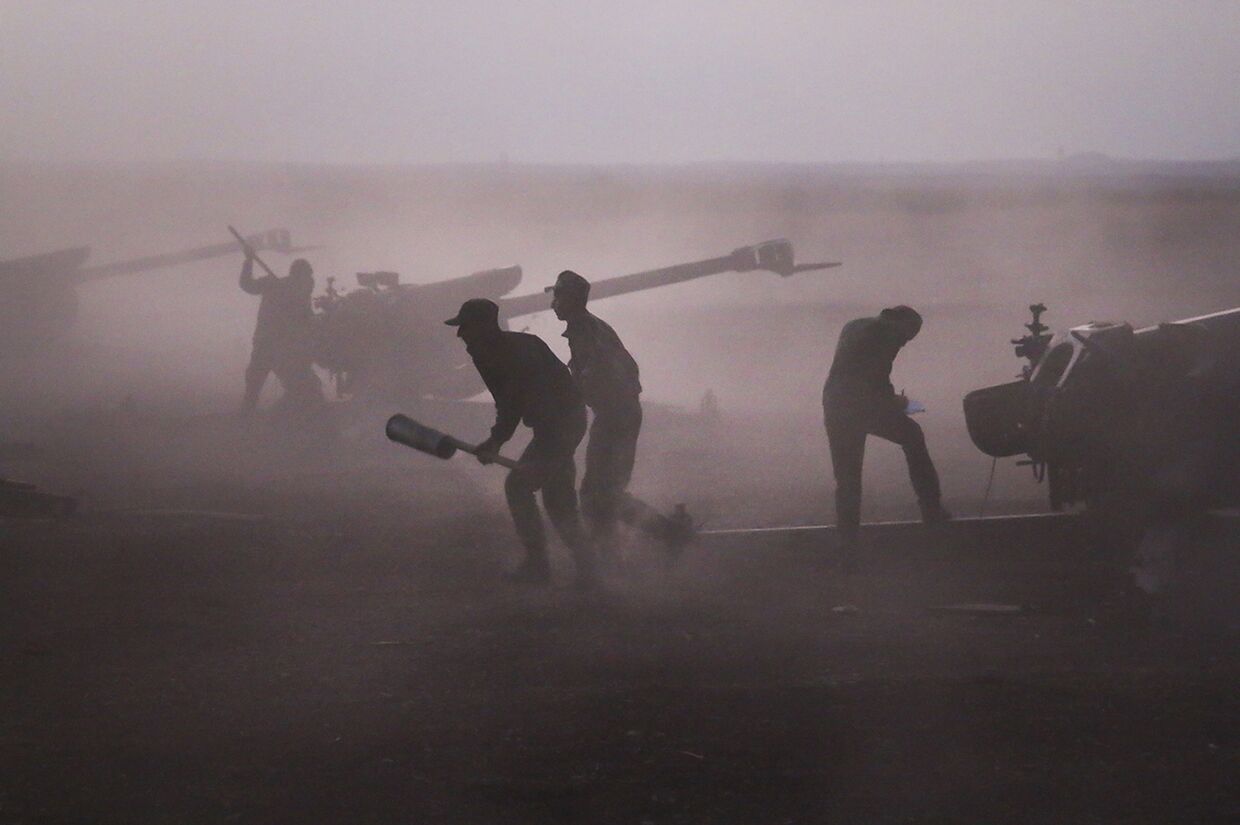 Военнослужащие сирийской армии загружают гаубицы рядом с деревней Морек