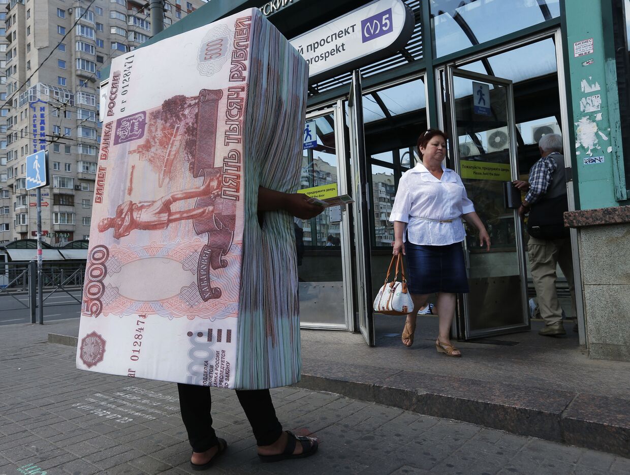 Человек в костюме пачки пятирублевых банкнот раздает флаеры у выхода из метро в Санкт-Петербурге