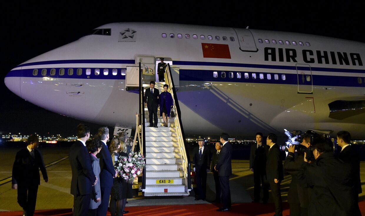 Председатель КНР Си Цзиньпин и его жена Пэн Лиюань спускаются по трапу самолета после прибытия в аэропорт Хитроу
