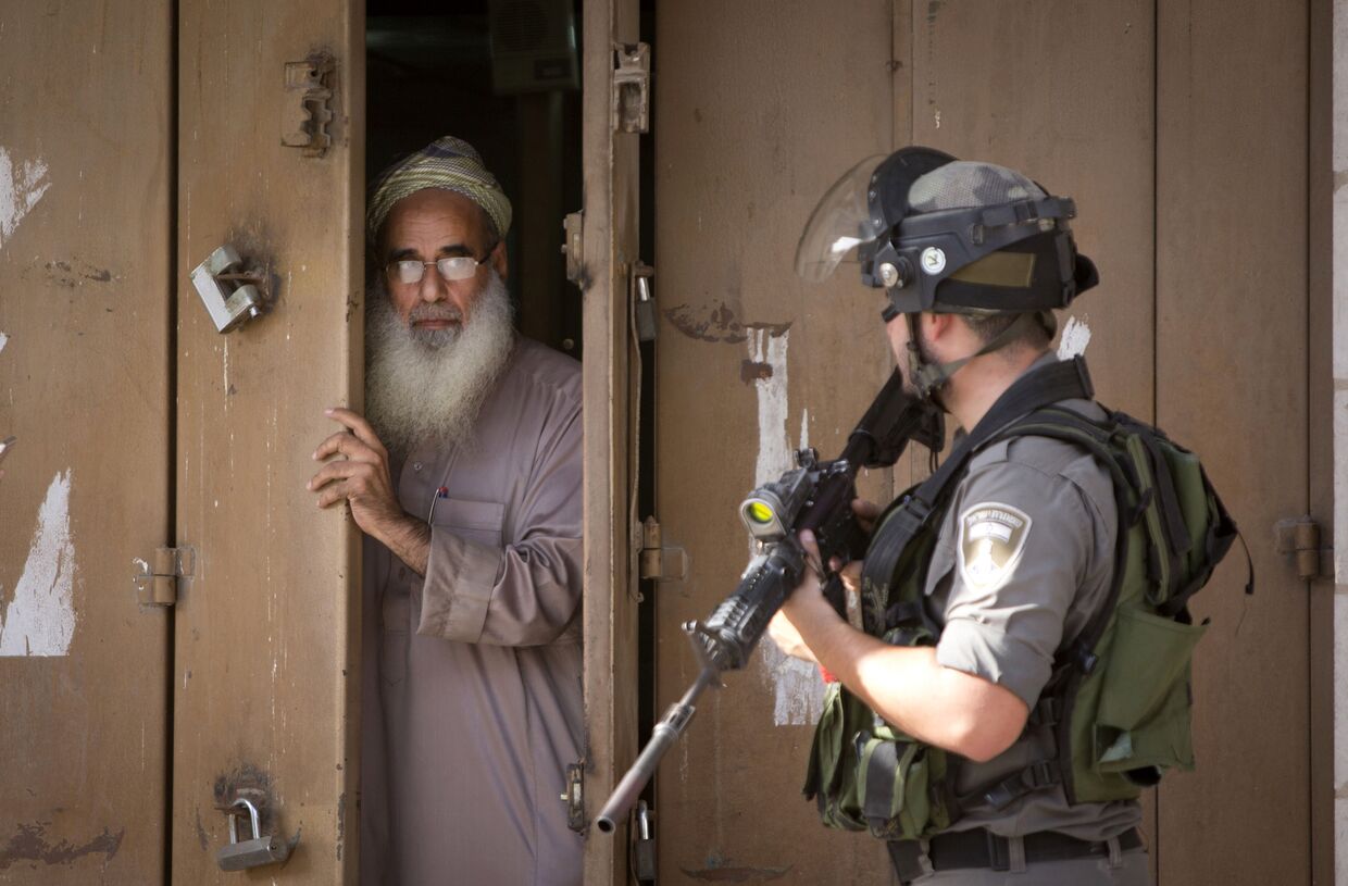 Пожилой житель города Аль-Рам закрывает свой магазин во время столкновений протестующих с израильской полицией