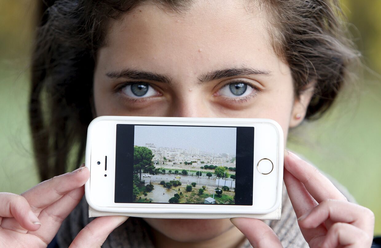 Беженка Хая из Сирии показывает фотографию своего родного города