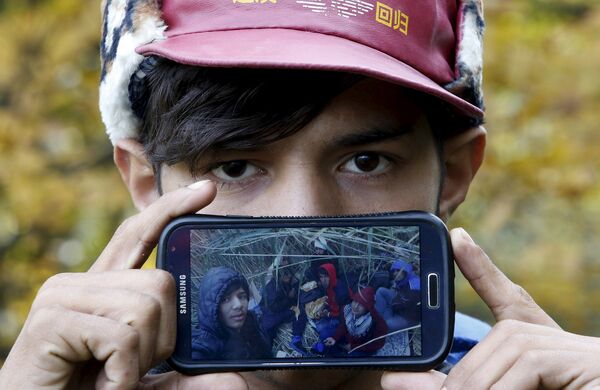 Акрам, беженец из города Герат в Афганистане, показывает фотографию своих друзей