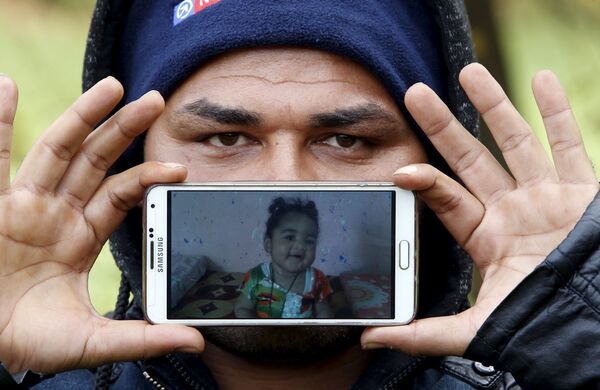 Назар, беженец из города Басра в Ираке, показывает фотографию своей дочери Шехед