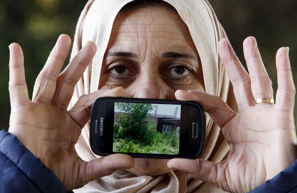 Лоджин, беженка из Хамсло в Сирии, показывает фотографию своего дома