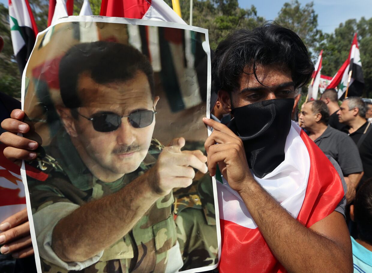 Сириец с плакатом с изображением Башара Асада на митинге в Бейруте
