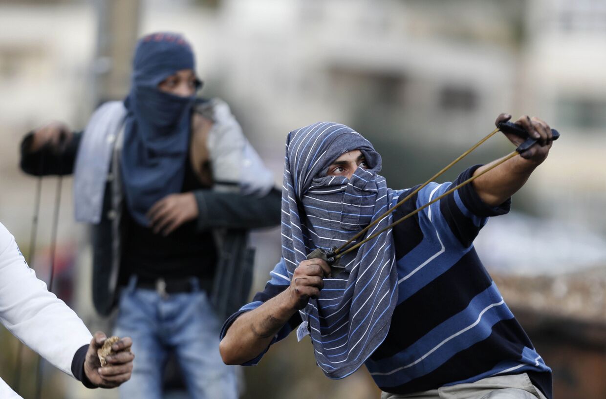 Палестинцы кидают камни во время столкновений с израильскими солдатами