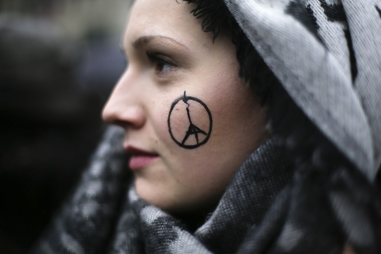 Символ «Мир Парижу» на лице у девушки во время минуты молчания у французского посольства в Берлине