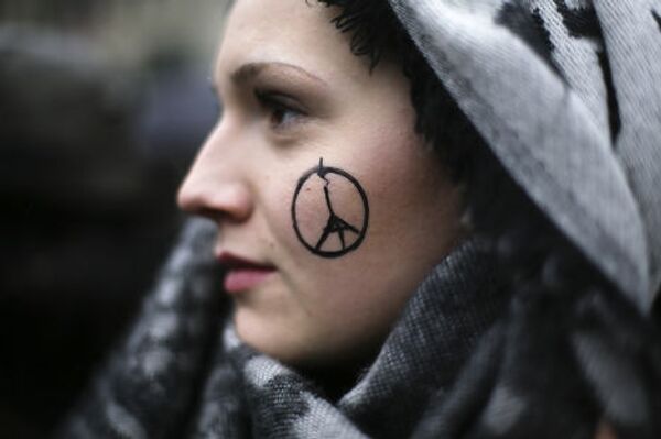 Символ «Мир Парижу» на лице у девушки во время минуты молчания у французского посольства в Берлине