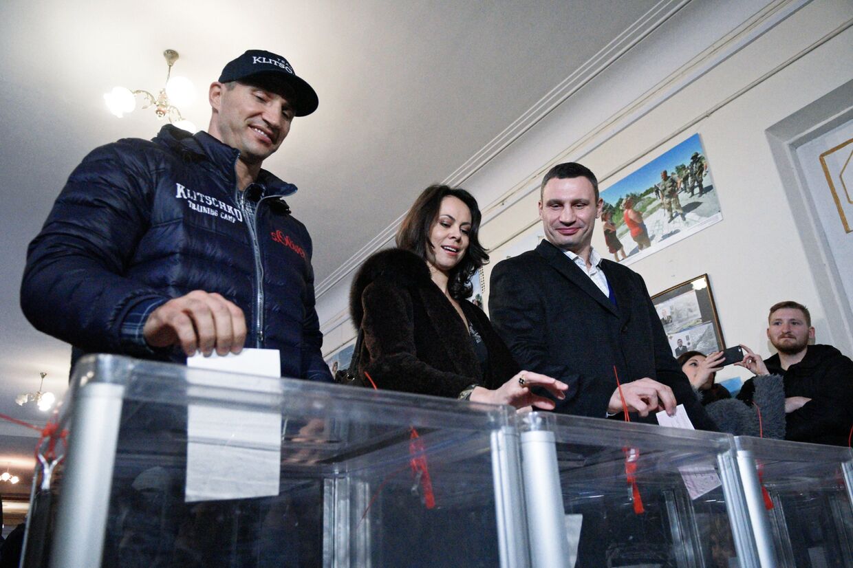 Лидер объединенной партии Солидарность, мэр Киева Виталий Кличко с супругой Натальей и его брат Владимир Кличко (справа налево) на избирательном участке в Киеве во время второго тура выборов в органы местного самоуправления.