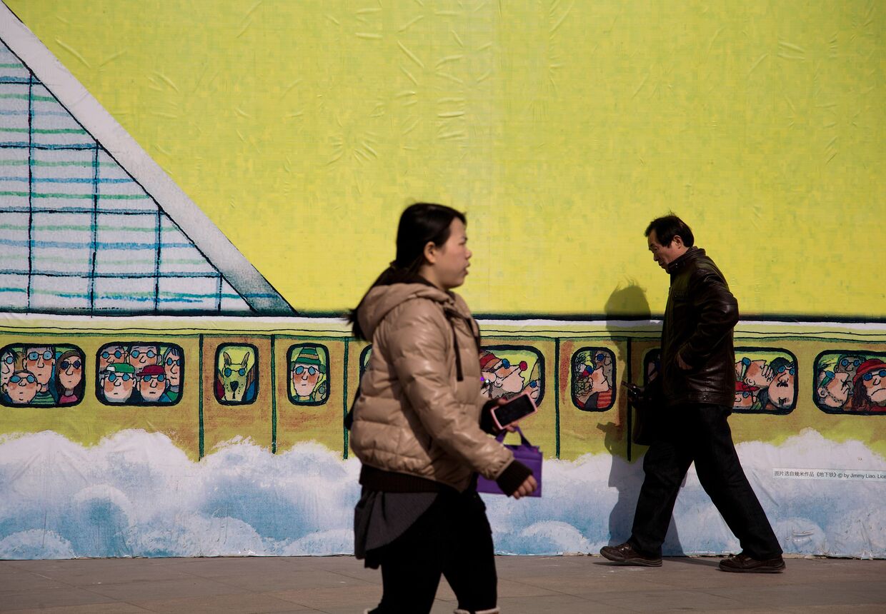 Люди проходят мимо рисунка на стене торгового центра в Пекине