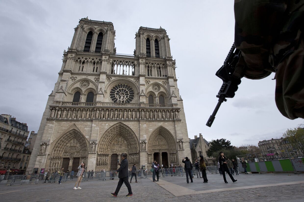 Солдат патрулирует площадь перед собором Парижской Богоматери в Париже