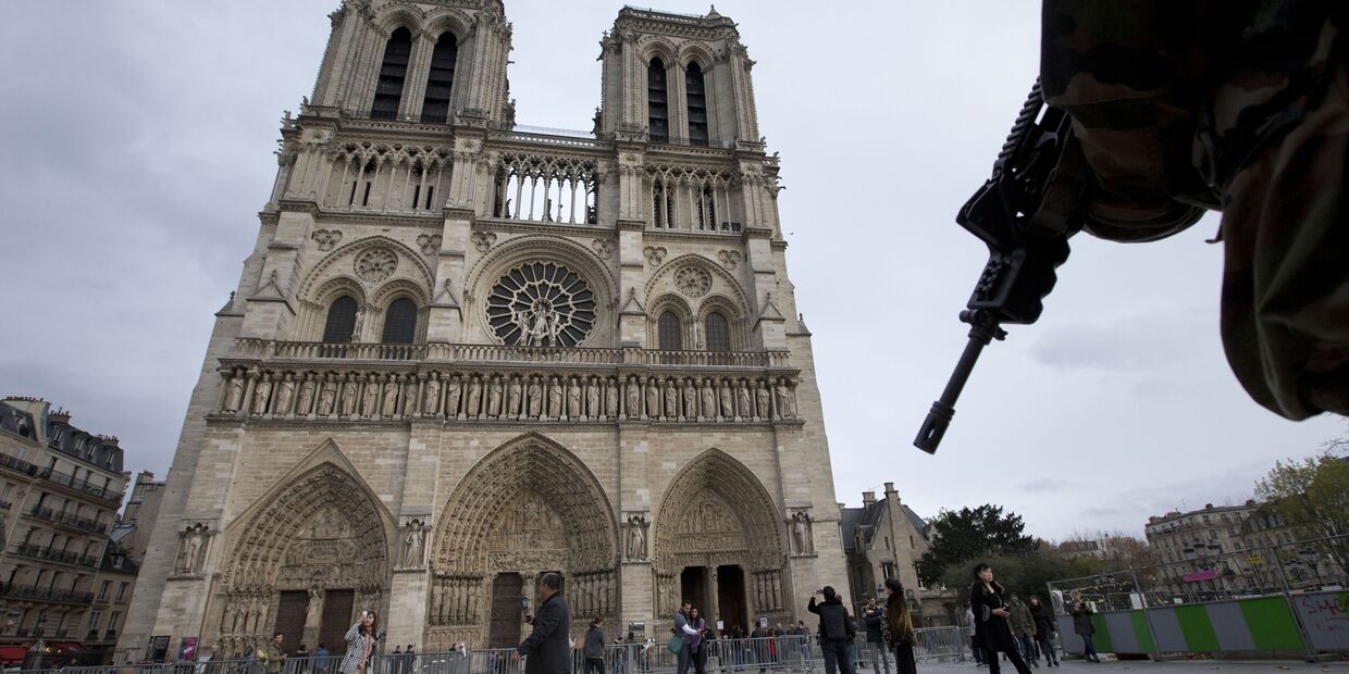 Солдат патрулирует площадь перед собором Парижской Богоматери в Париже