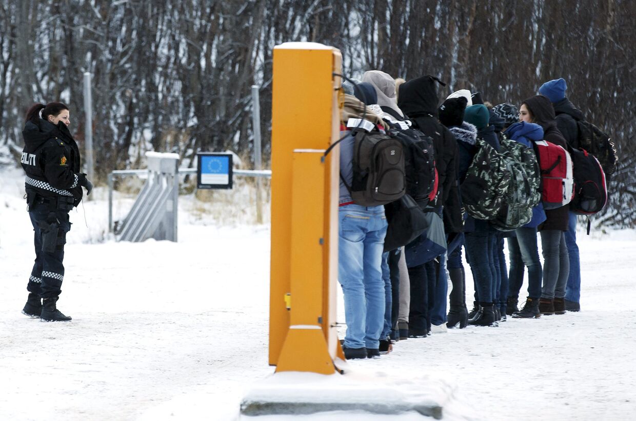 Норвежский офицер полиции инструктирует мигрантов после пересечения российско-норвежской границы