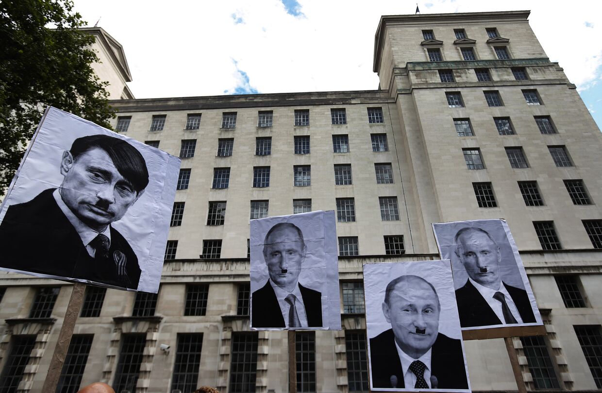 Плакаты, изображающие Владимира Путина в образе Адольфа Гитлера, во время акции протеста в Лондоне