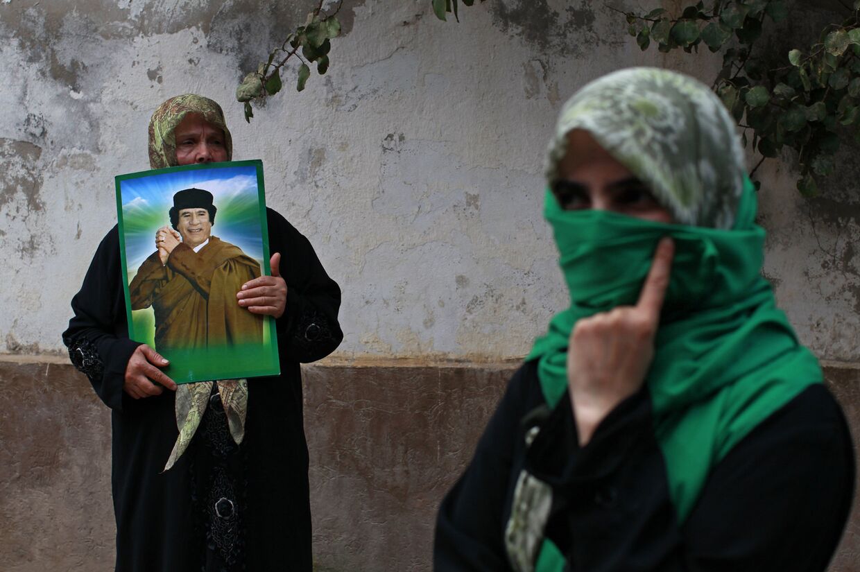 Женщины с портретом Муаммара Каддафи на акции протеста против авиударов НАТО у здания посольства Венгрии в Триполи, апрель 2011 года