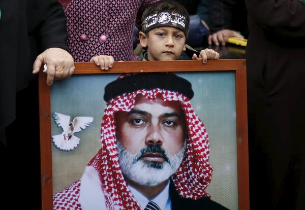 Мальчик с портретом лидера ХАМАС Исмаила Хании на параде в Газе в честь 28-летия основания движения