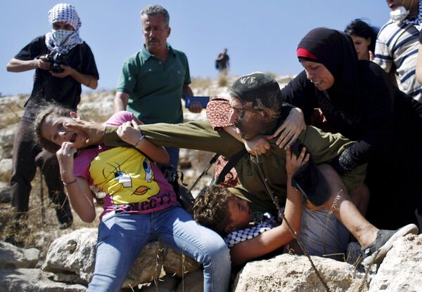 Палестинцы пытаются помешать израильскому солдату задержать мальчика во время протеста против еврейских поселений в деревне Наби Салех