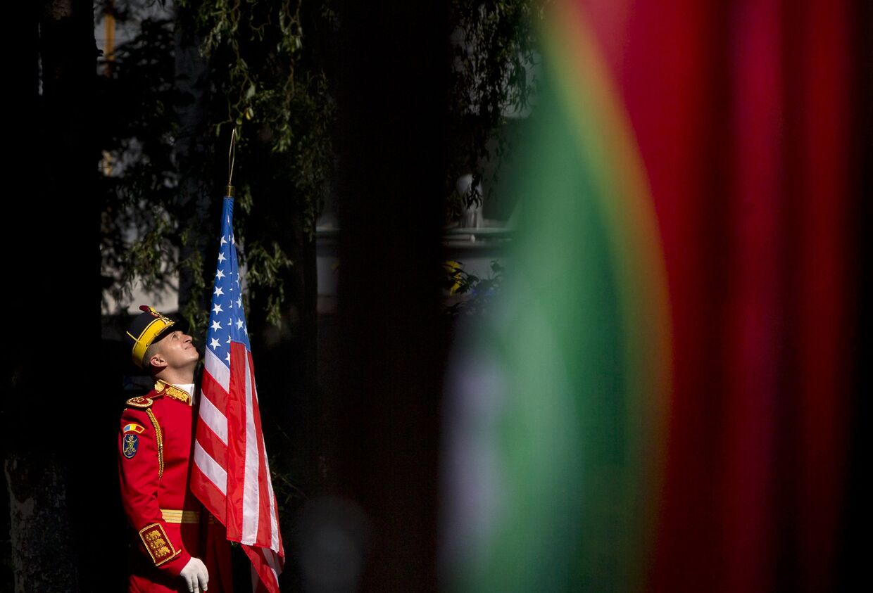 Румынский солдат держит флаг США во время церемонии открытия командного центра НАТО в Бухаресте