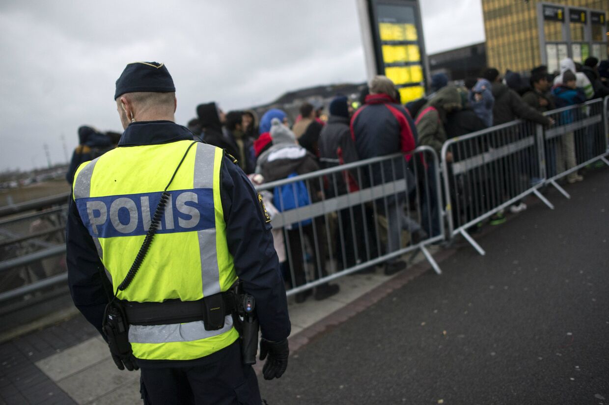 Полицейский следит за мигрантами в Швеции
