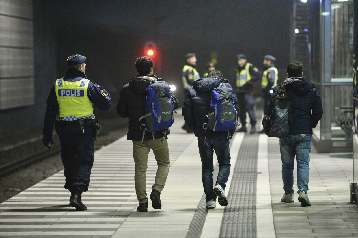 Полицейский сопровождает мигрантов в Швеции