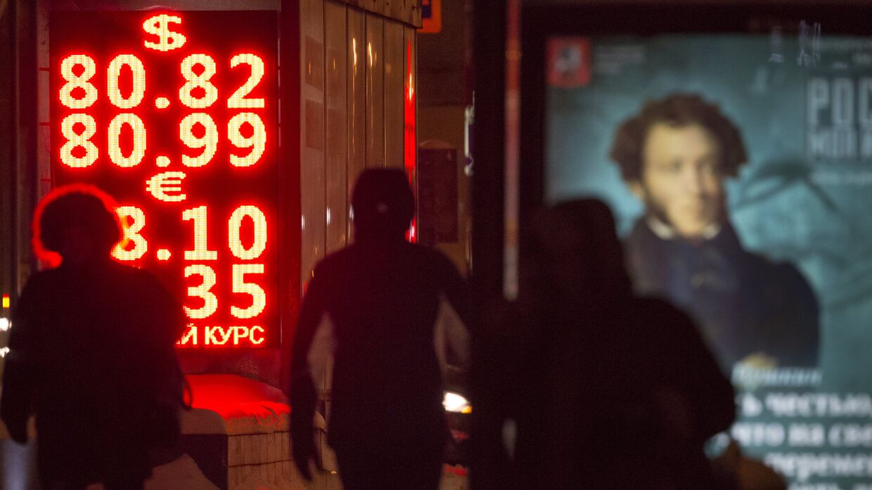 Прохожие идут мимо табло с информацией о курсах обмена валют в Москве