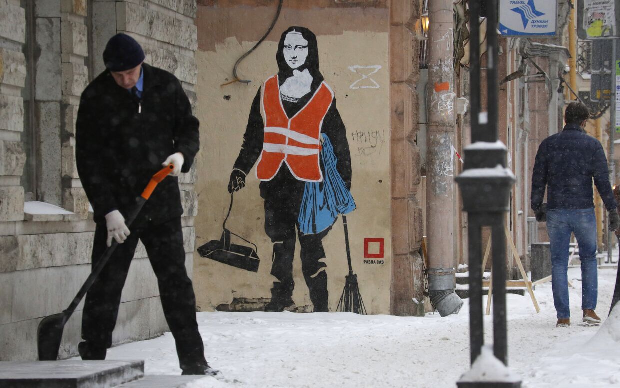 Мужчина чистит снег в Санкт-Петербурге